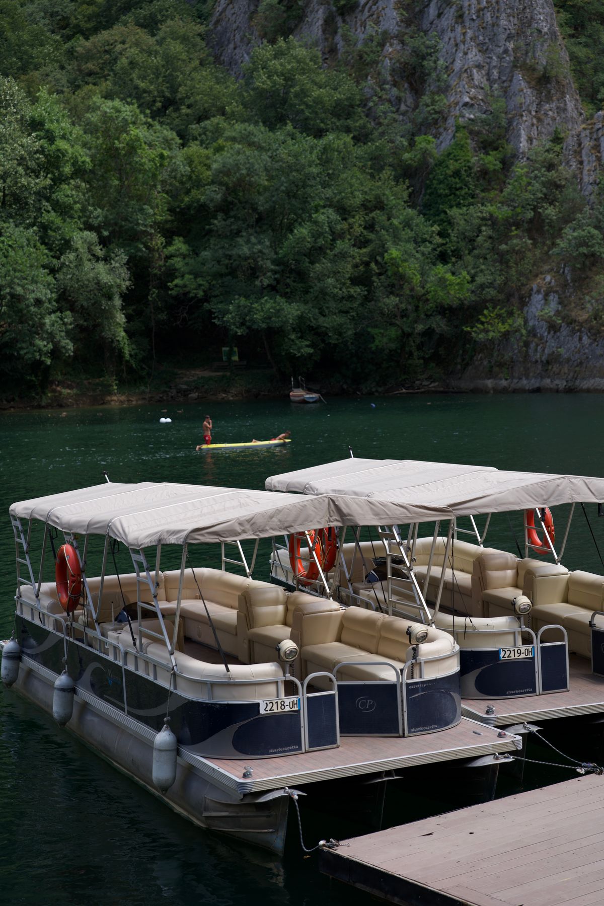 Pontoon boats tied at a wooden dock on a calm lake